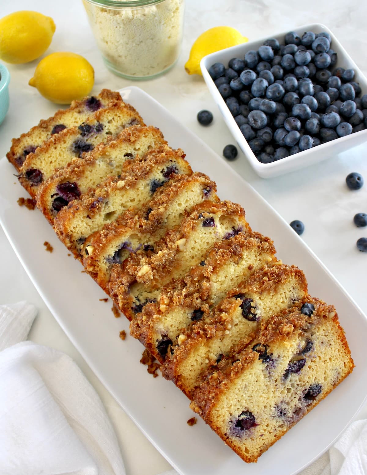 overhead view of Keto Blueberry Crumb Loaf cut into slices on white platter