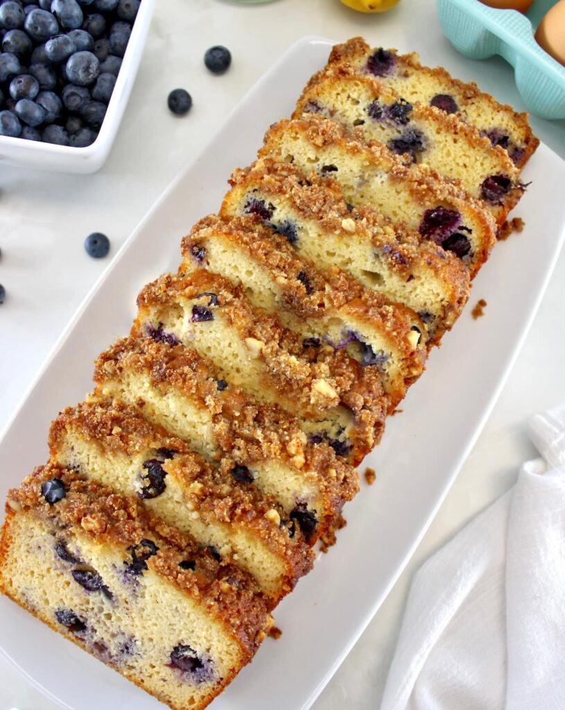 overhead view of Keto Blueberry Crumb Loaf cut into slices on white platter