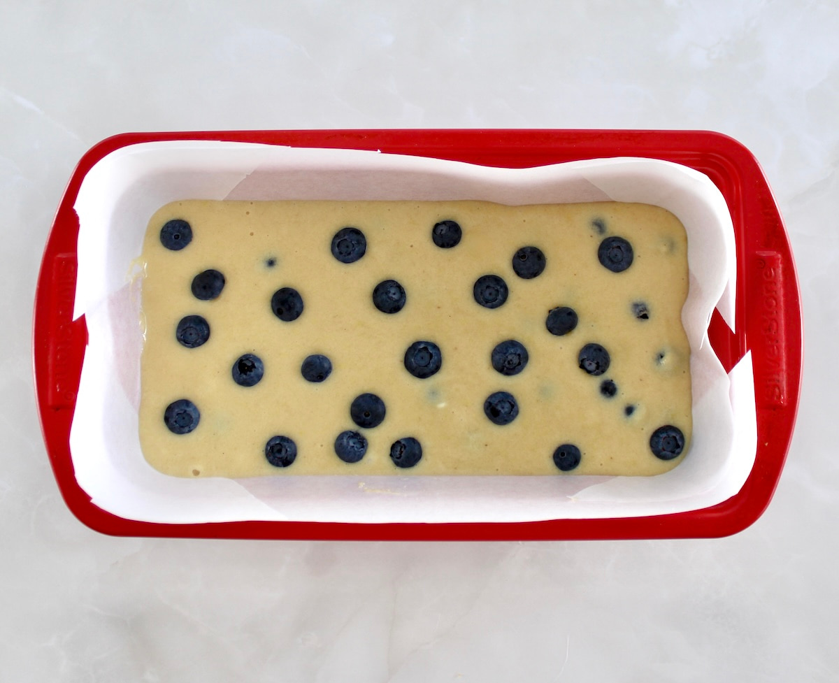 Keto Blueberry Crumb Loaf batter in red loaf pan with parchment paper