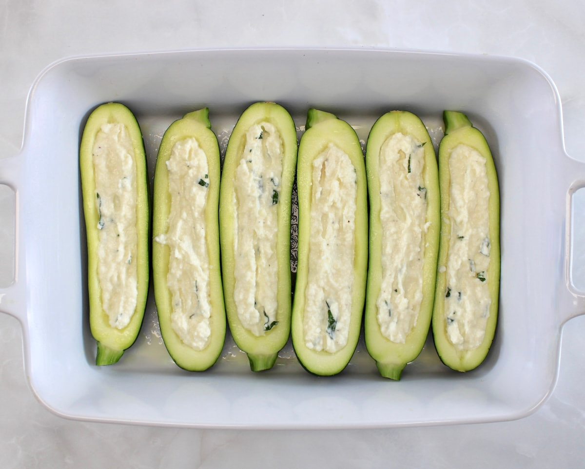 6 zucchini halves in white casserole with cheese stuffing