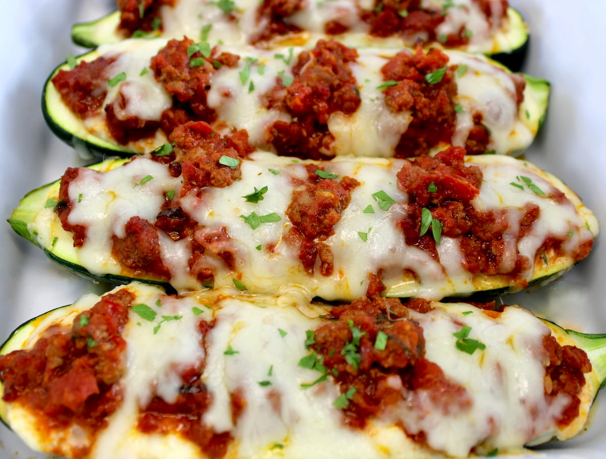 closeup of 3 Lasagna Stuffed Zucchini Boats in white casserole