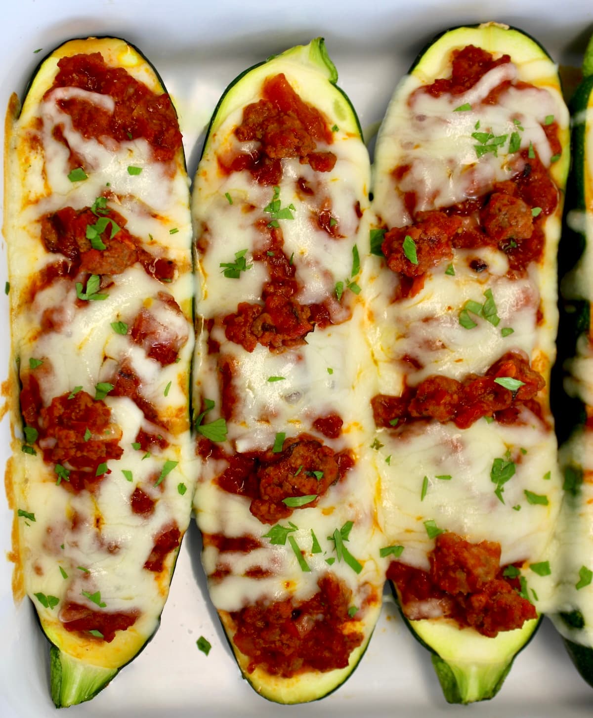 overhead view of 3 Lasagna Stuffed Zucchini Boats in white casserole