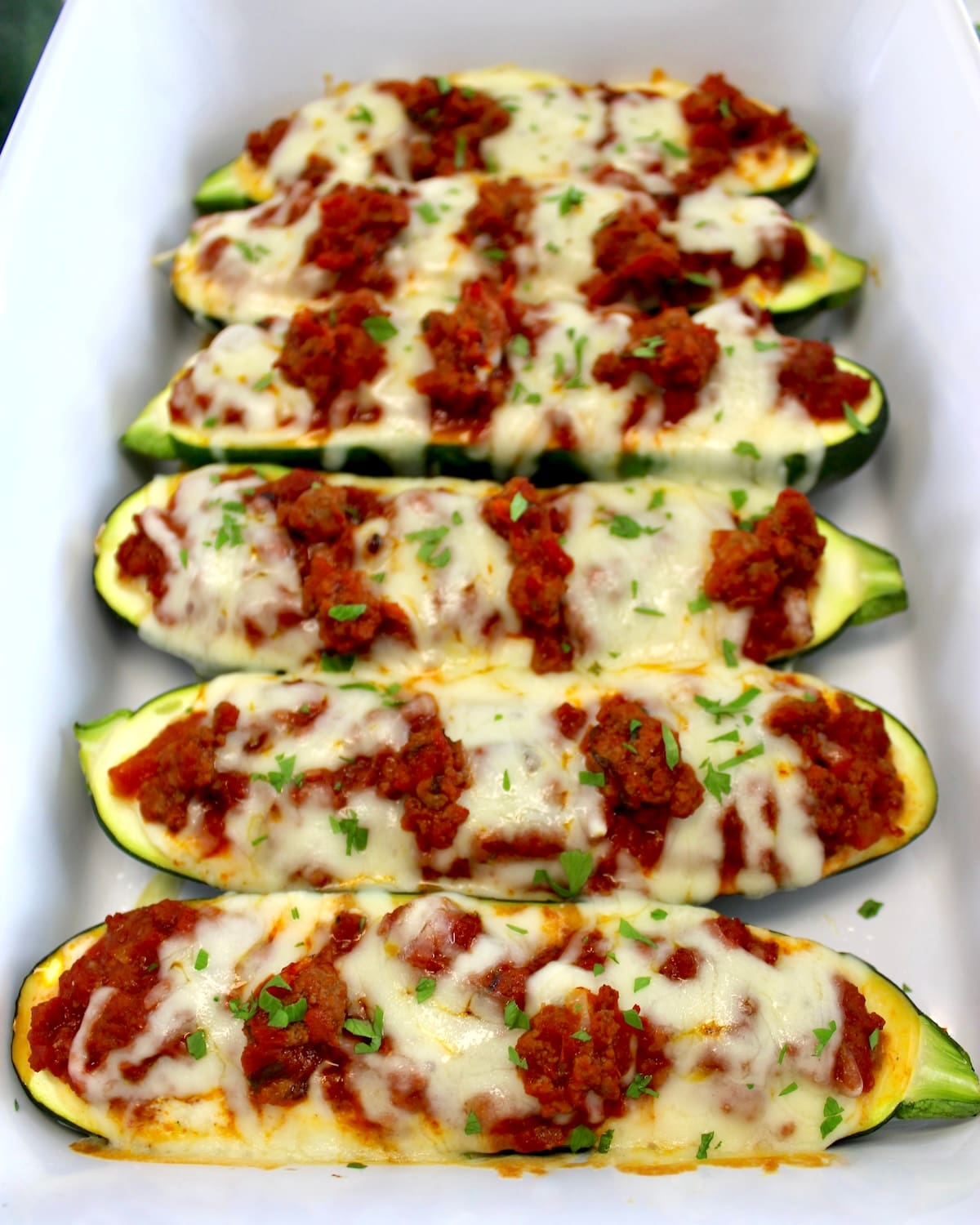 overhead view of Lasagna Stuffed Zucchini Boats lined up in white casserole