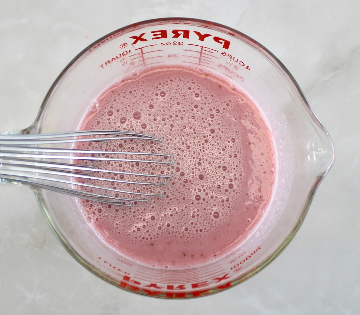whisking Strawberry Almond Milk in glass measuring bowl