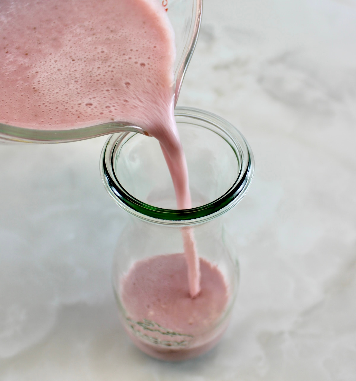 Strawberry Almond Milk being poured into glass bottle
