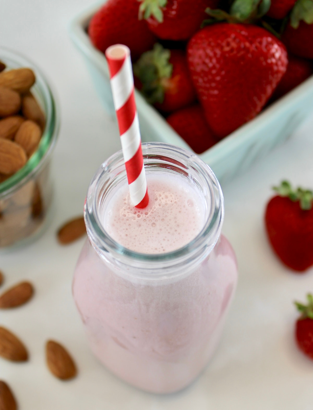 overhead view of Strawberry Almond Milk in glass bottle with red and white straw