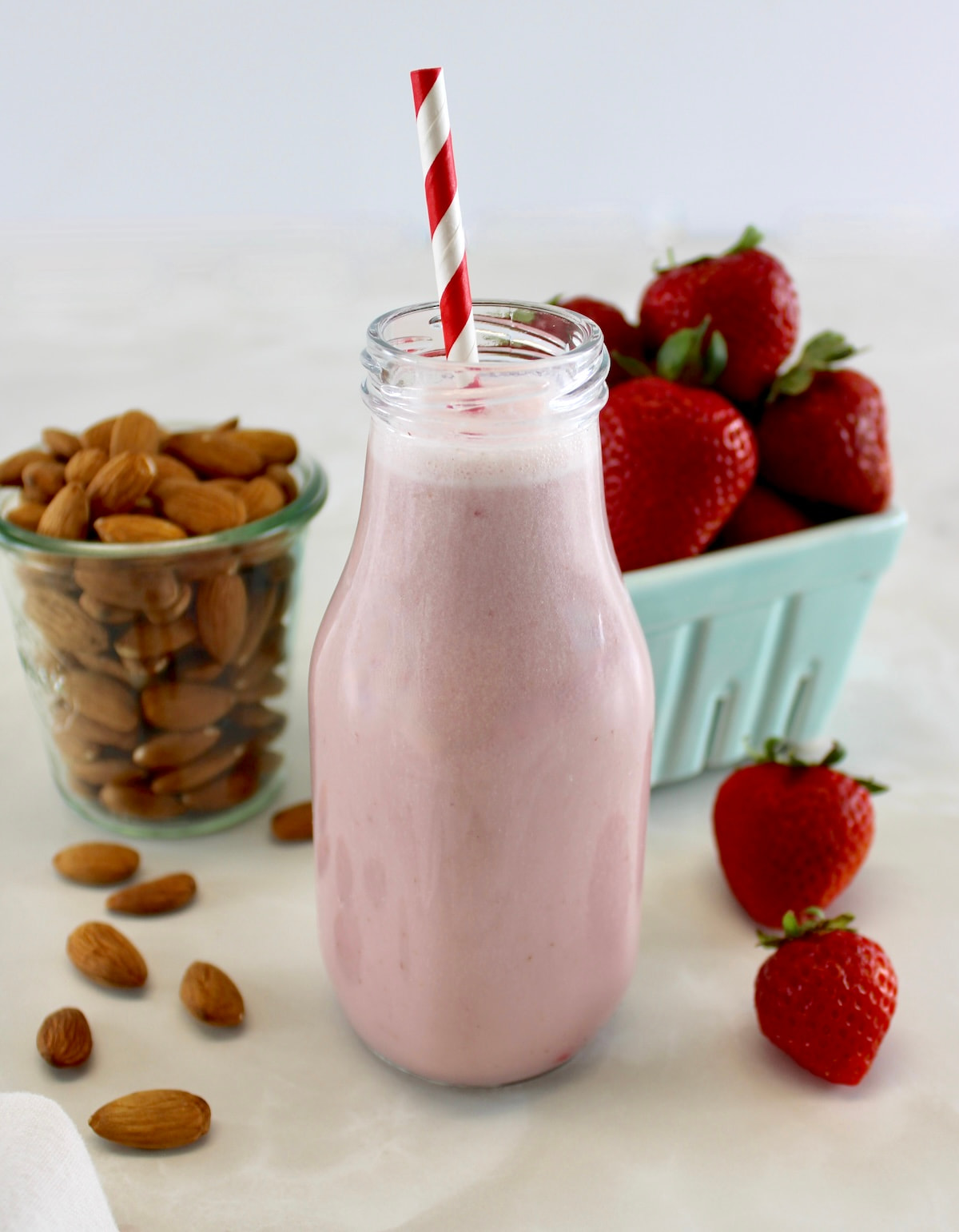 closeup side view of Strawberry Almond Milk in glass bottle with red and white straw