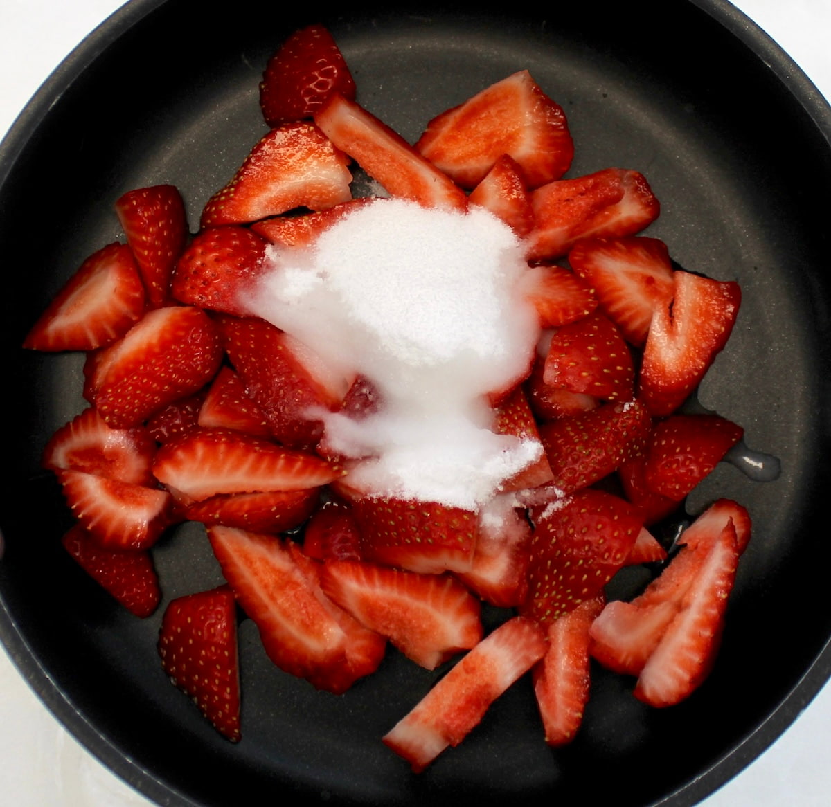cut up strawberries and sweetener in saucepan