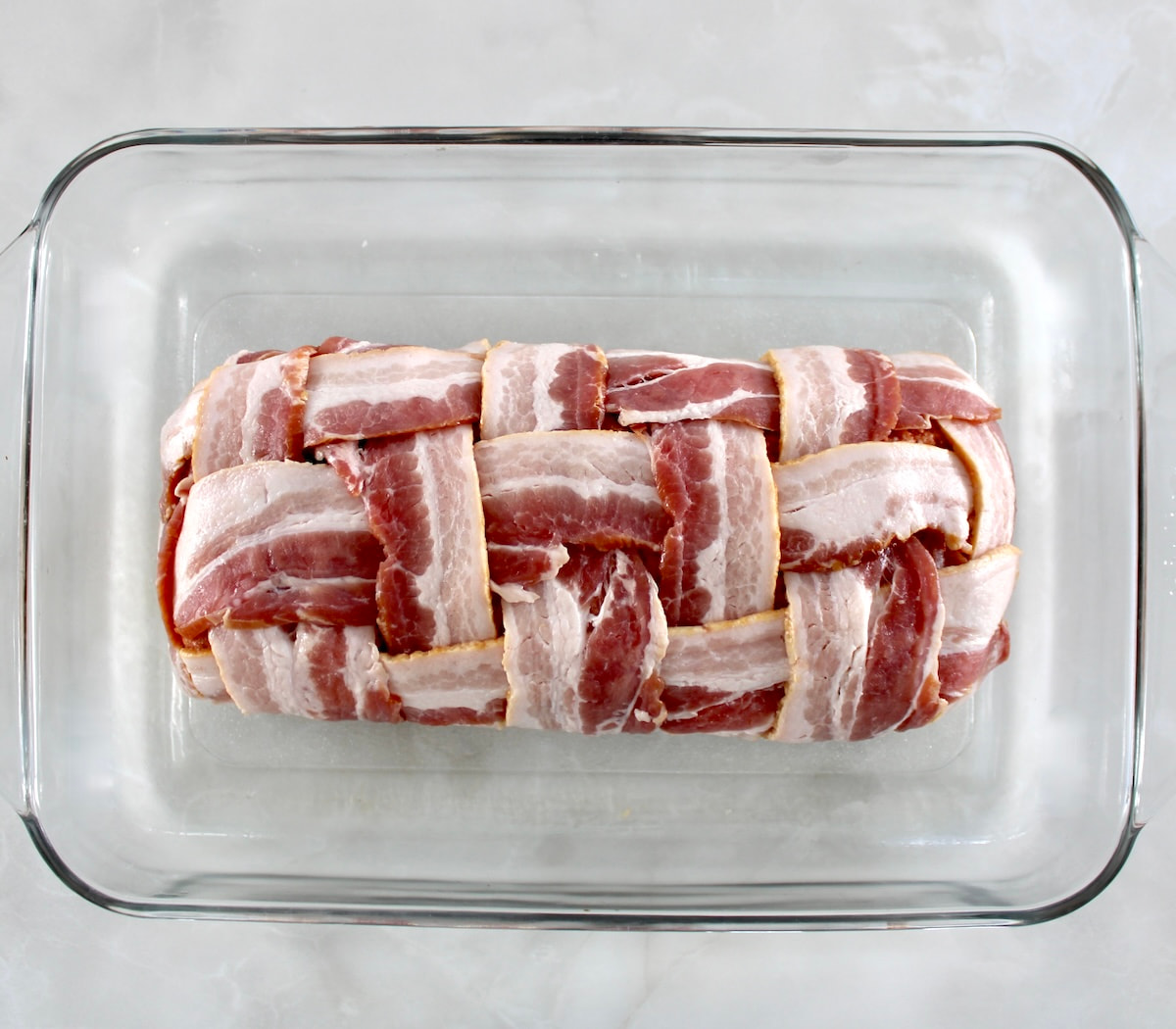 Bacon Wrapped Cheese Stuffed Italian Meatloaf unbaked in glass baking dish
