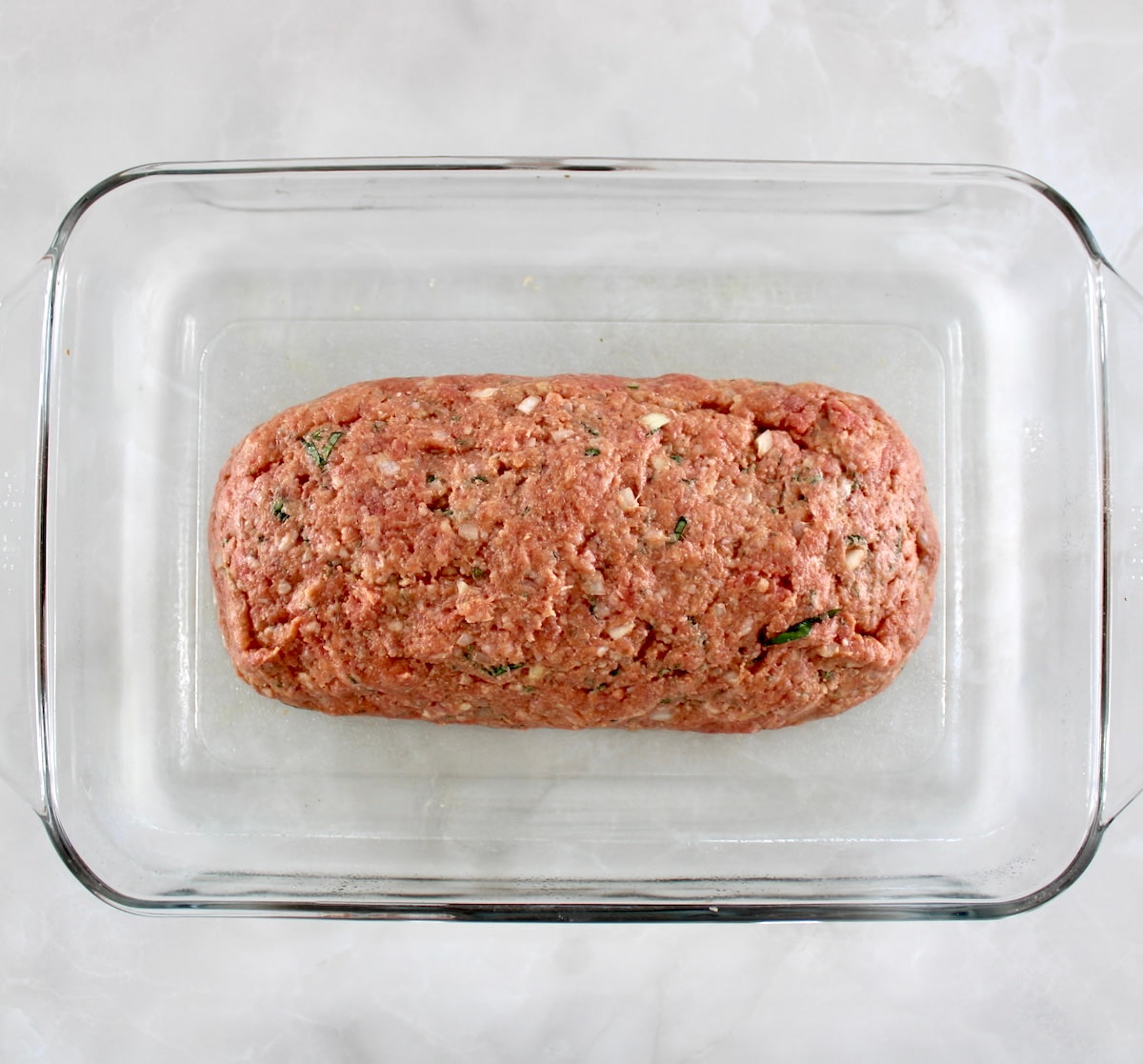 Bacon Wrapped Cheese Stuffed Italian Meatloaf unbaked in glass casserole dish
