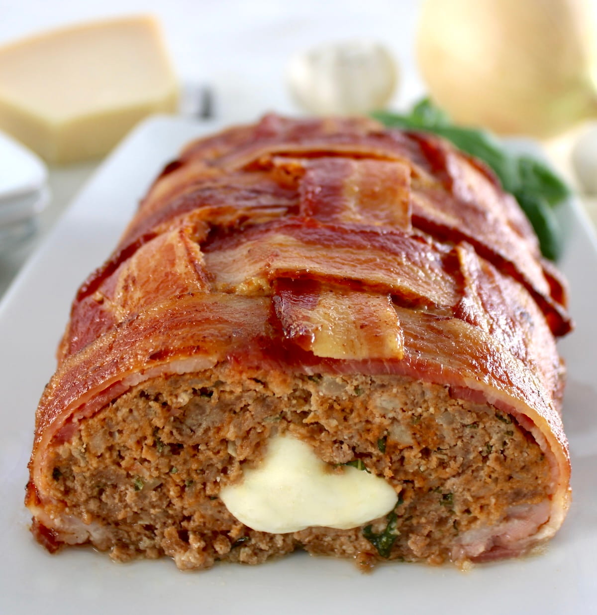 closeup of Bacon Wrapped Cheese Stuffed Italian Meatloaf on white plate