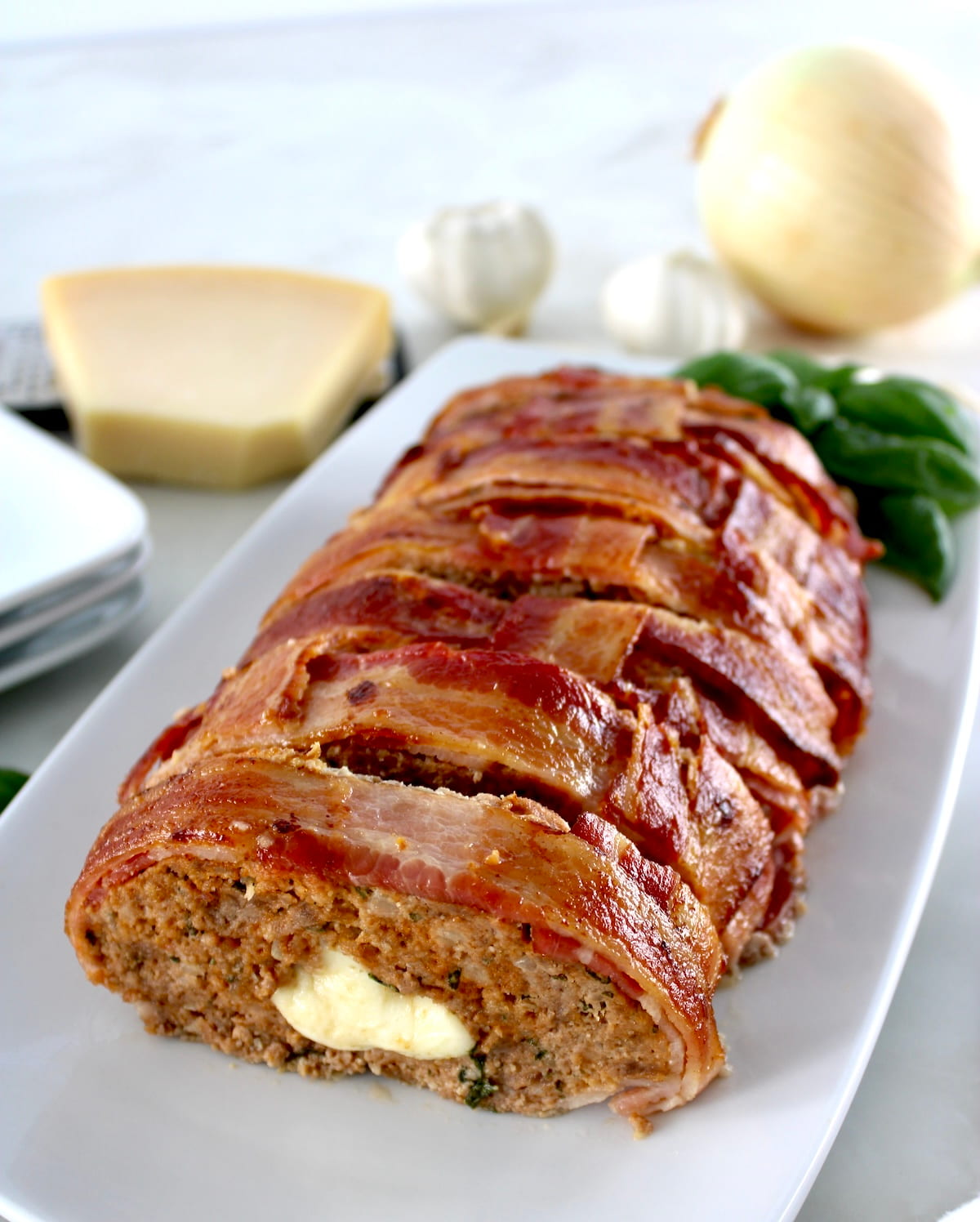Bacon Wrapped Cheese Stuffed Italian Meatloaf with end sliced off on white plate