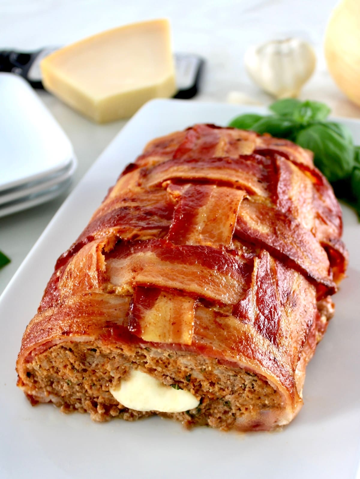 Bacon Wrapped Cheese Stuffed Italian Meatloaf with end sliced off on white plate