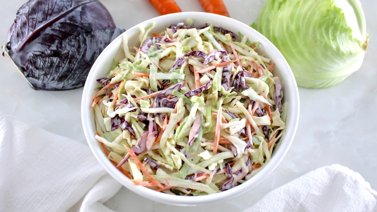 Easy Keto Coleslaw in white bowl with cabbage in back