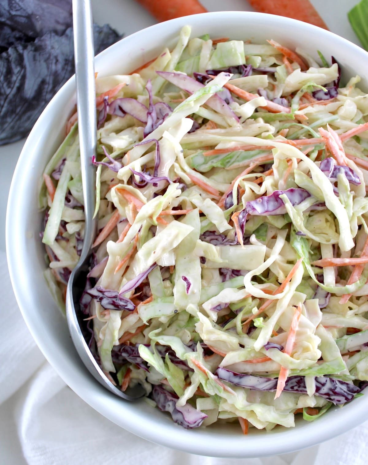 Easy Keto Coleslaw in a white bowl with silver serving spoon on side