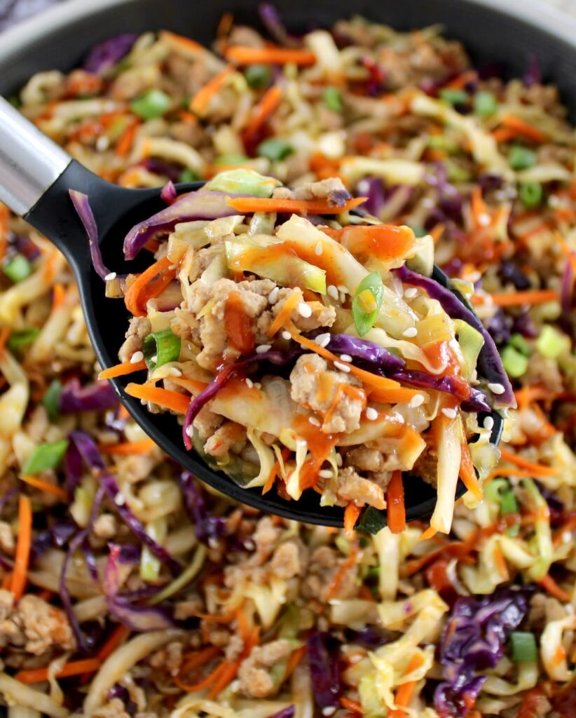 Keto Egg Roll in a Bowl in black serving spoon held up over skillet