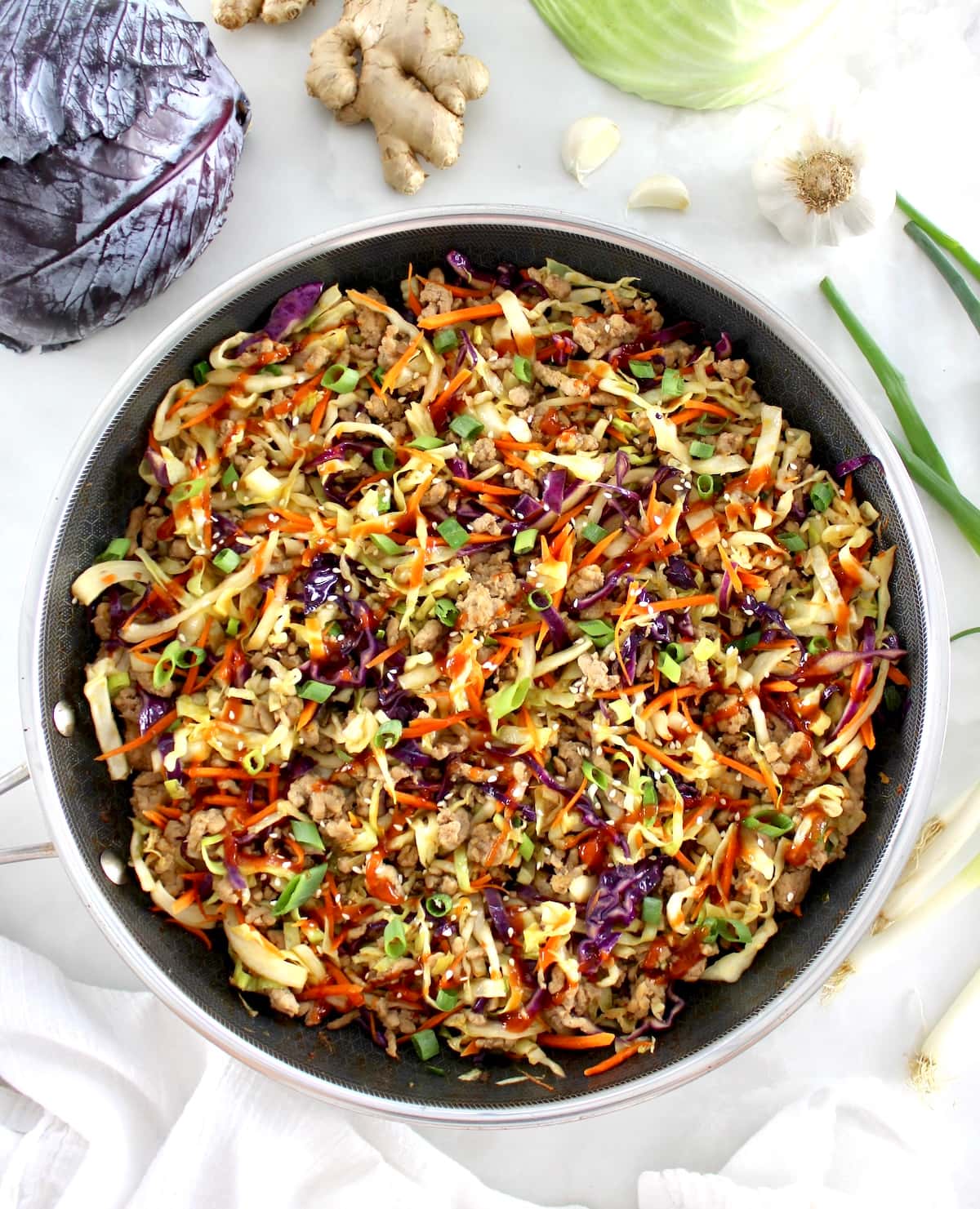 overhead view of Keto Egg Roll in a Bowl in skillet with cabbage and ginger in back