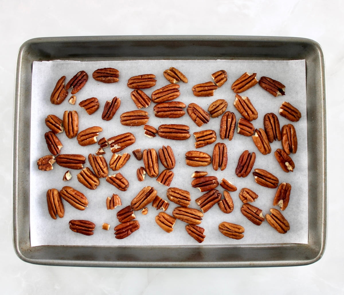 pecan halves on parchment lined baking sheet