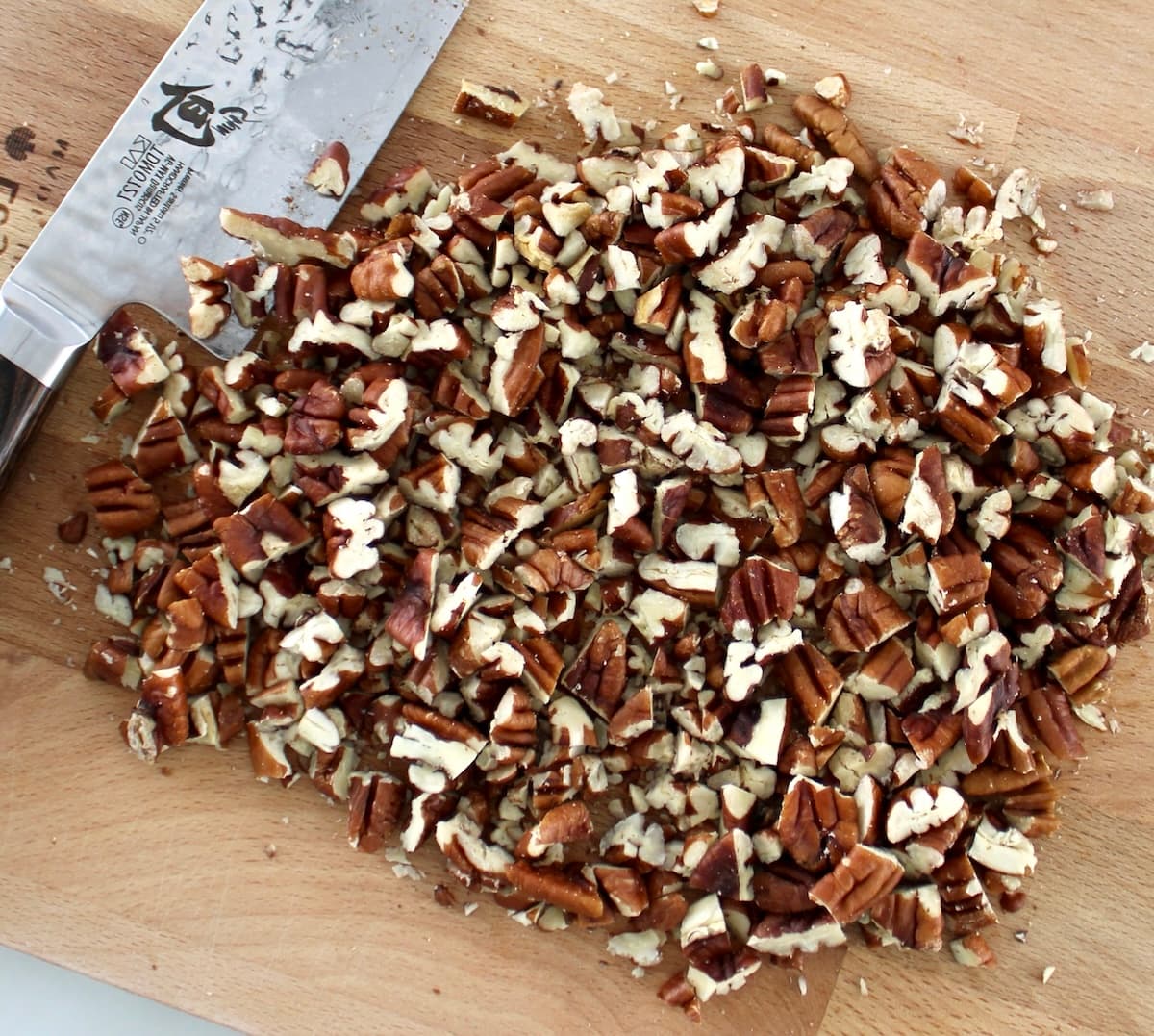 chopped pecans on cutting board with knife