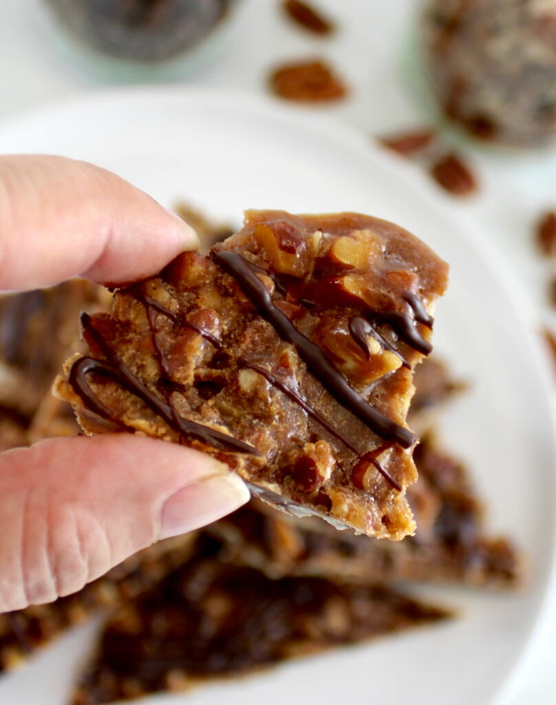 holding up small piece of Keto Pecan Praline Bark