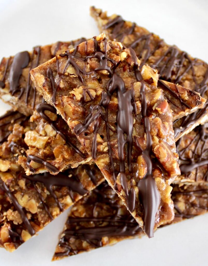 closeup of Keto Pecan Praline Bark stacked up on white plate