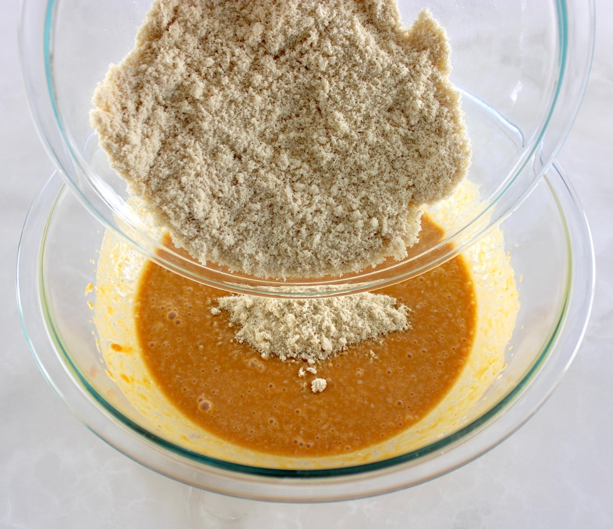 dry ingredients being poured into the wet for Keto Pumpkin Cream Cheese Swirl Muffins