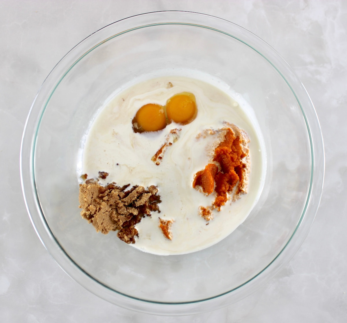 wet ingredients for Keto Pumpkin Cream Cheese Swirl Muffins in glass bowl unmixed