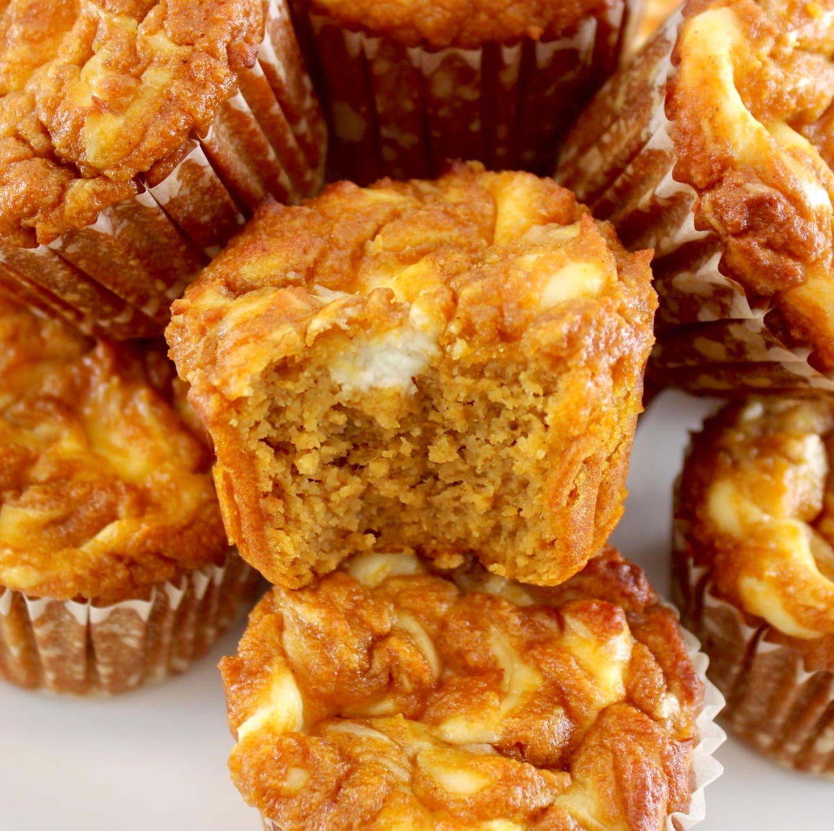 Keto Pumpkin Cream Cheese Swirl Muffins stacked up with bite missing from one in center