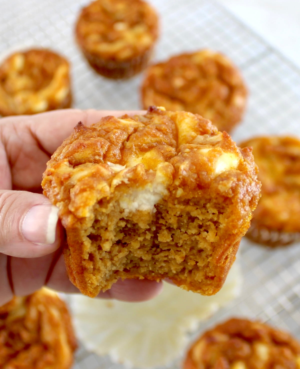 holding up Keto Pumpkin Cream Cheese Swirl Muffin with bite missing