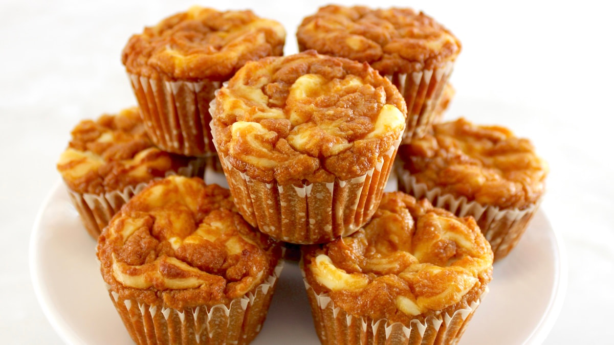 Keto Pumpkin Cream Cheese Swirl Muffins stacked up on white plate