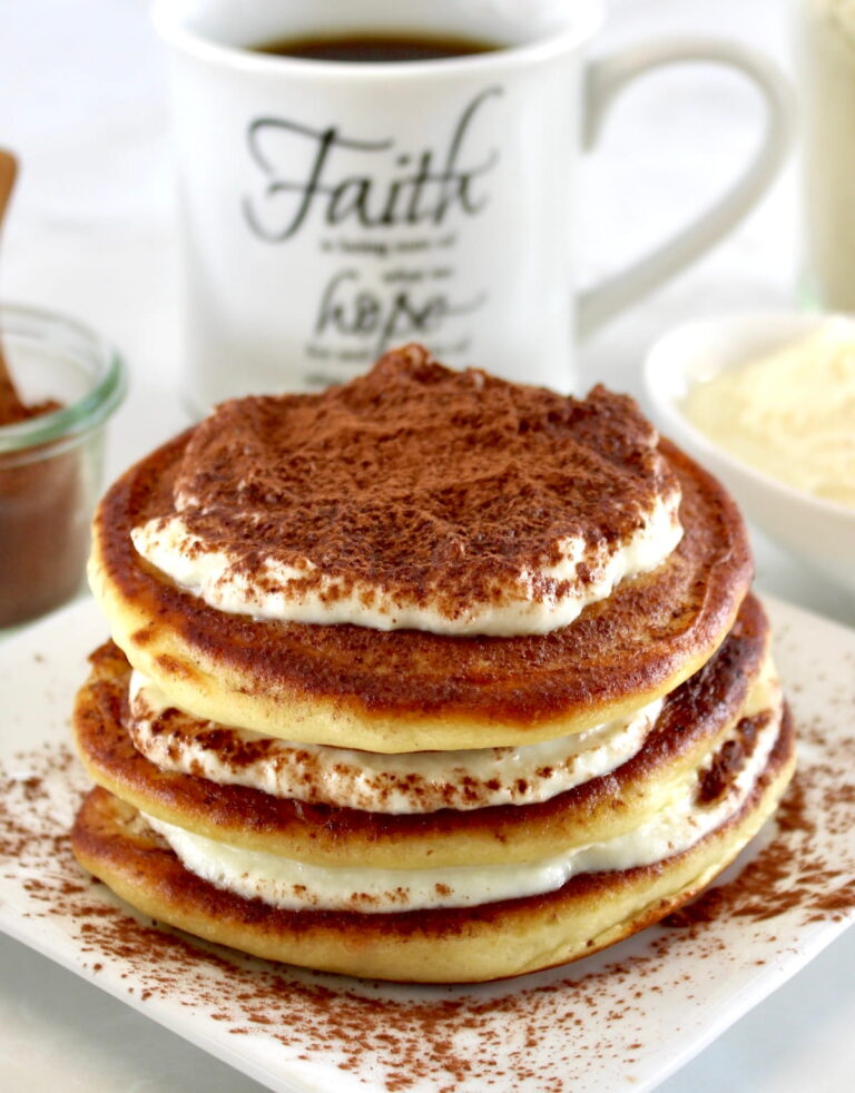 Keto Tiramisu Pancakes stacked on white plate with mug of coffee in back