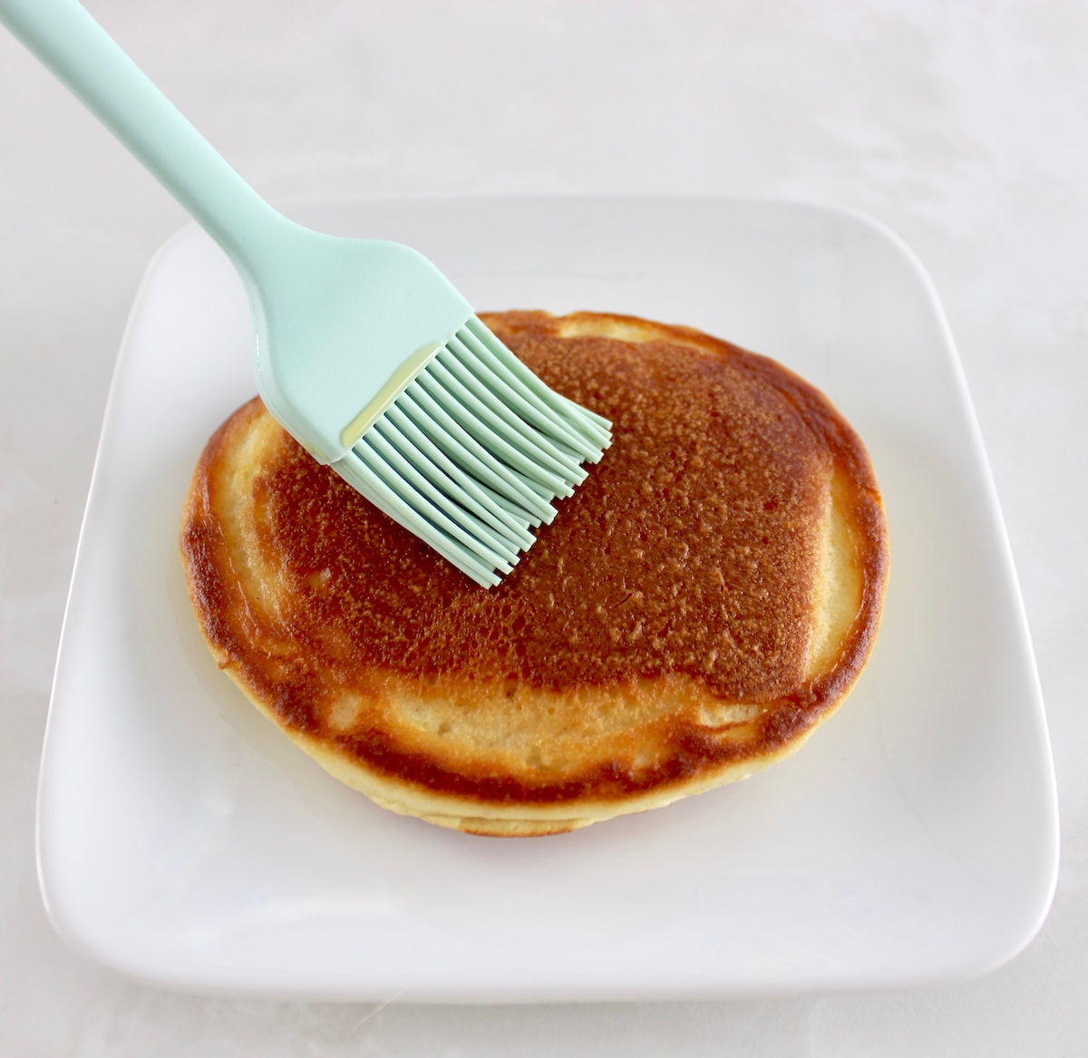 coffee being brushed on pancake on white plate