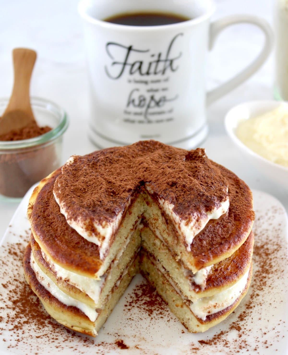 closeup of Keto Tiramisu Pancakes with bite missing and mug of coffee in back