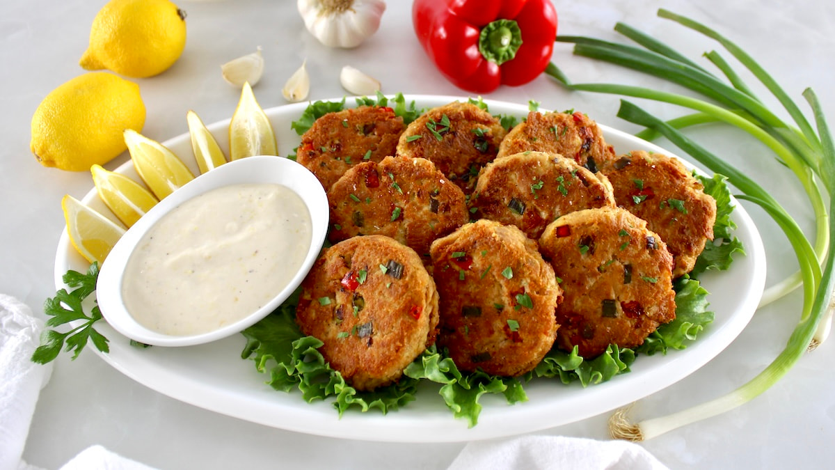 Tuna Cakes on white oval platter with garlic aioli and lemon slices