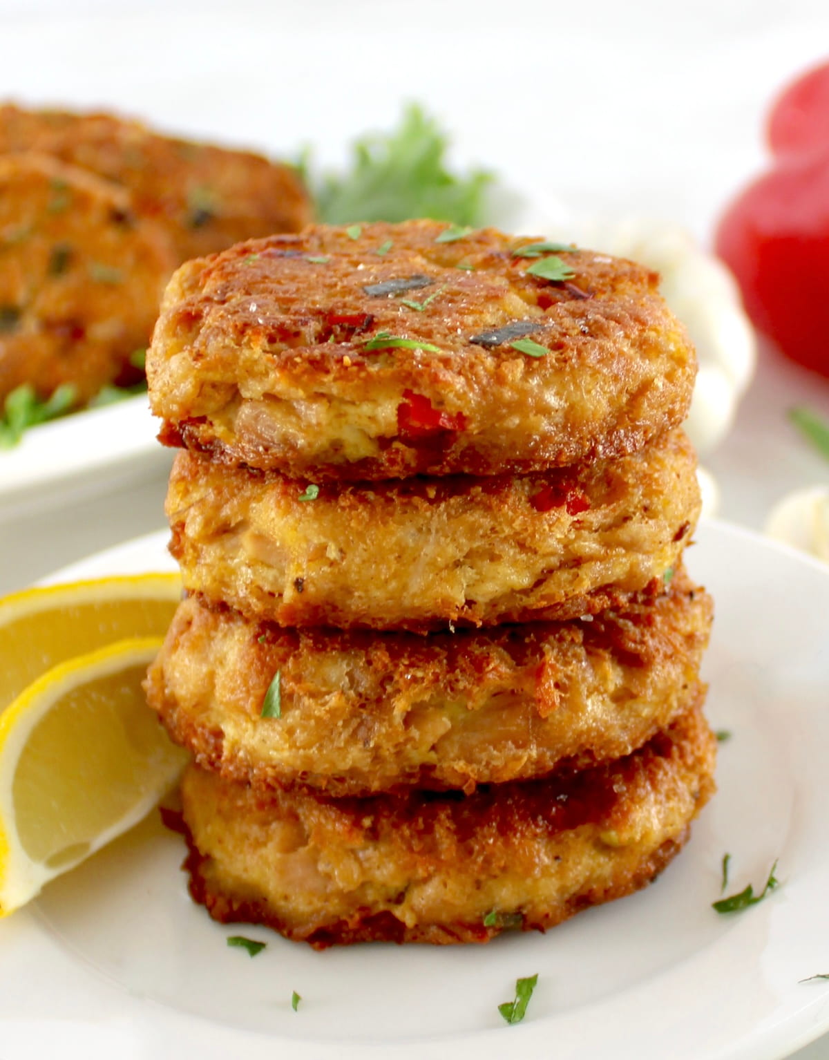 closeup of 4 Tuna Cakes on white plate with lemon wedges on side
