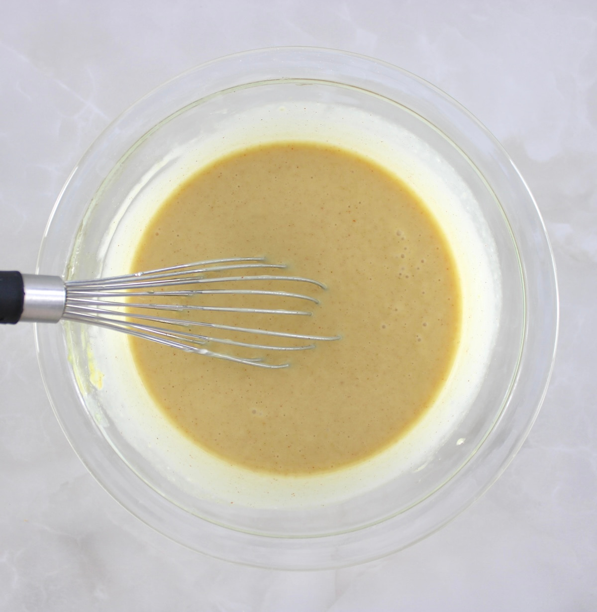 keto honey mustard dressing in glass bowl with whisk