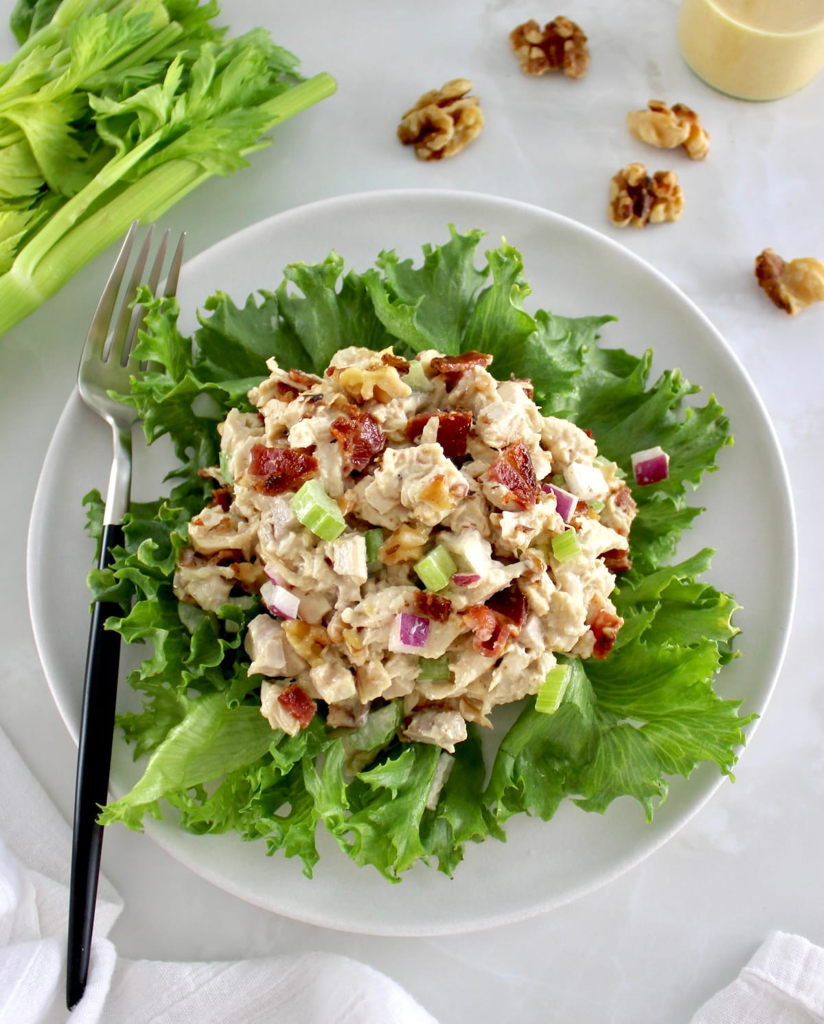 Bacon Honey Mustard Chicken Salad over lettuce on white plate with fork on side