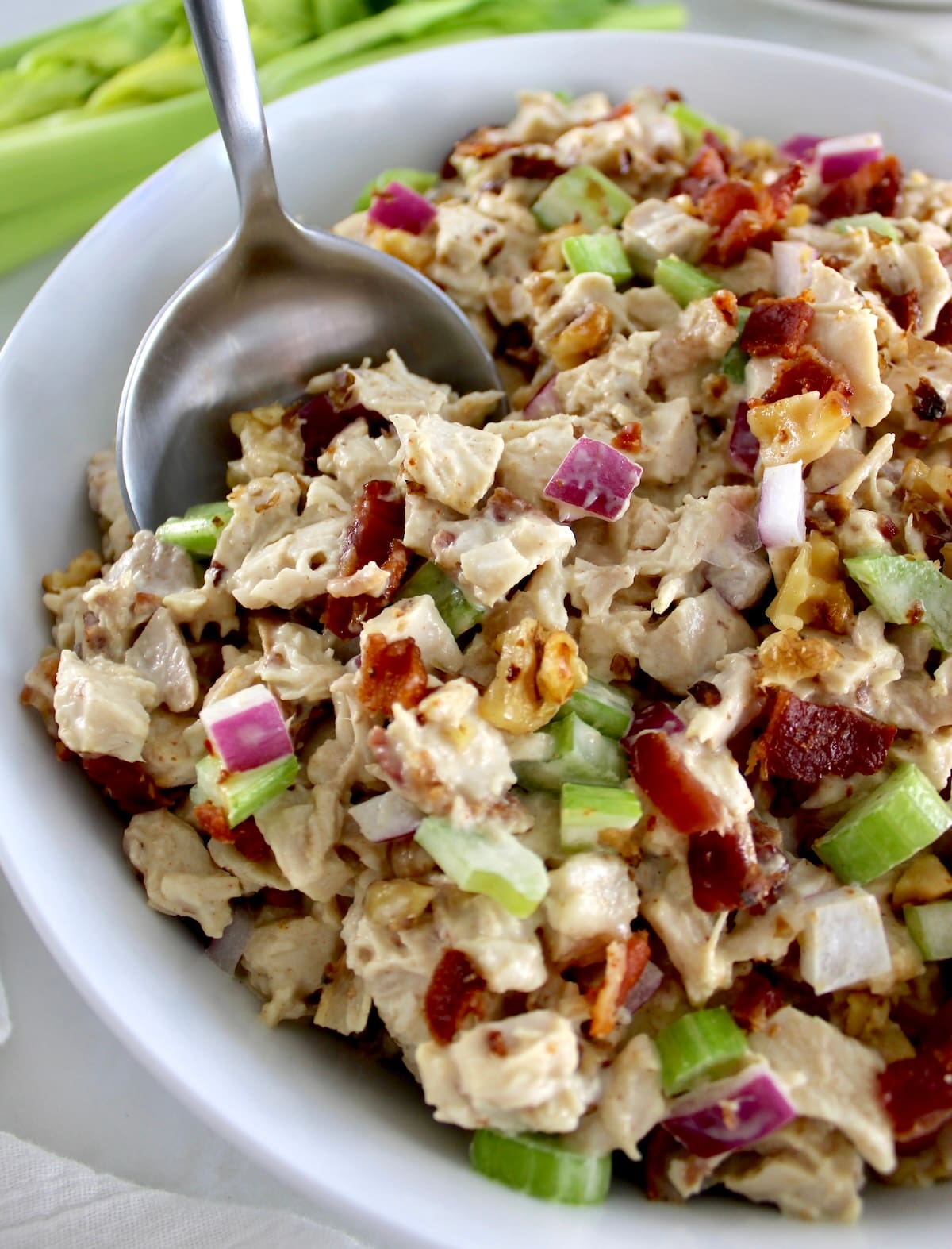 Bacon Honey Mustard Chicken Salad in white bowl with serving spoon scooping out some
