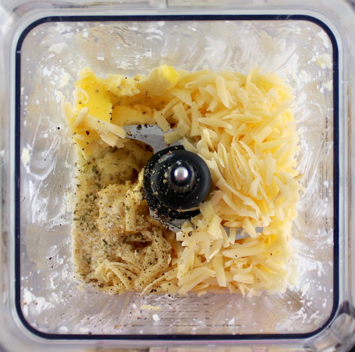 Cottage Cheese Cauliflower Mash ingredients in blender with shredded cheese and butter on top