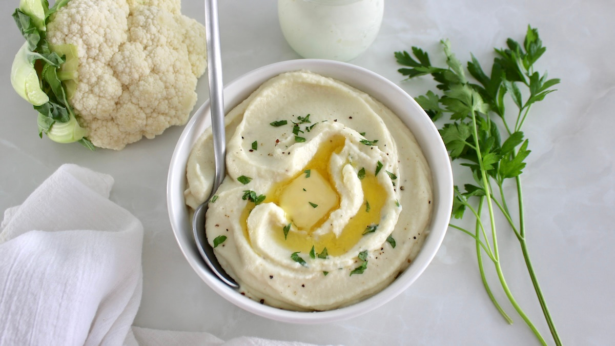 Cottage Cheese Cauliflower Mash in white bowl with butter and spoon on side