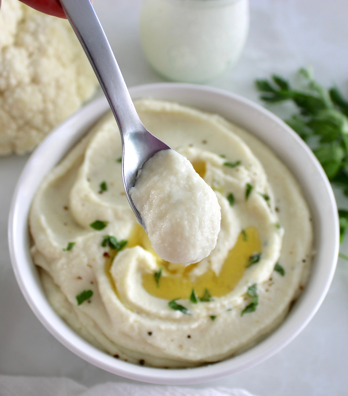 spoonful of Cottage Cheese Cauliflower Mash held up over white bowl