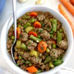 Ground Beef Stew in white bowl with silver spoon on side
