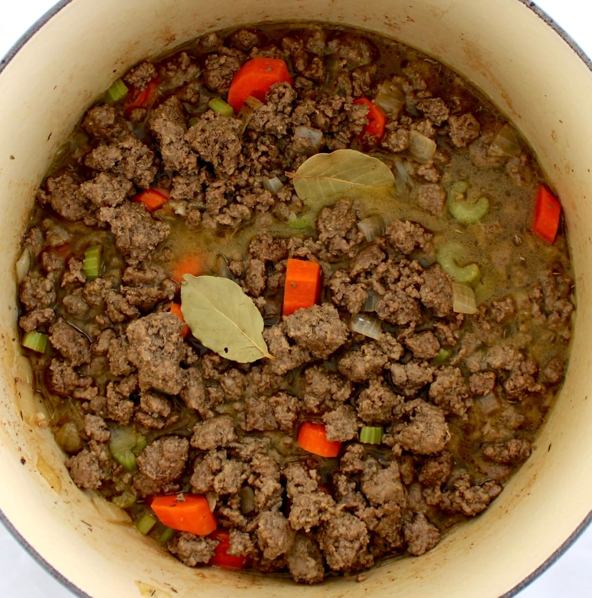 Ground Beef Stew cooking in pot with 2 bay leaves
