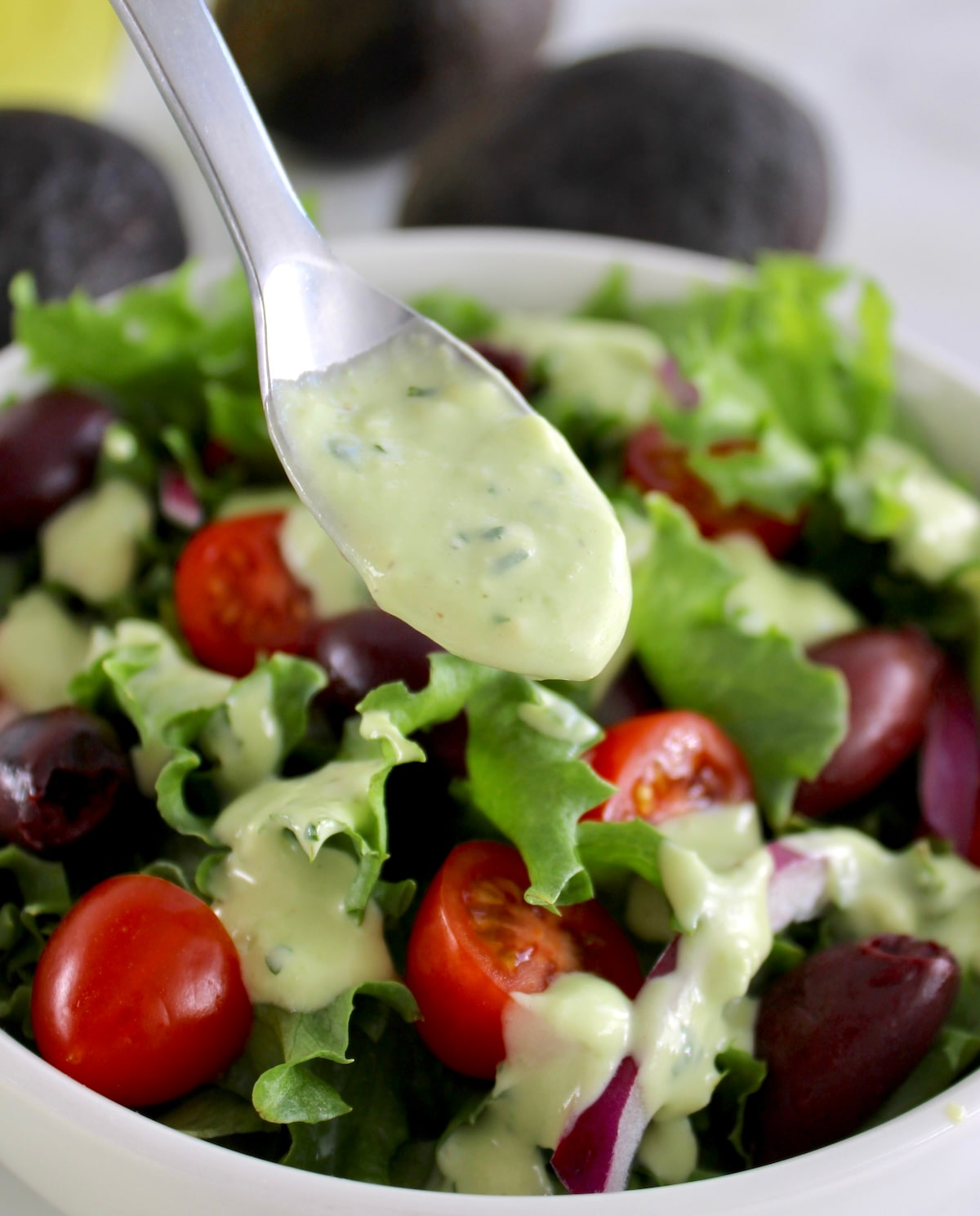 spoon with Keto Avocado Ranch Dressing held up over salad
