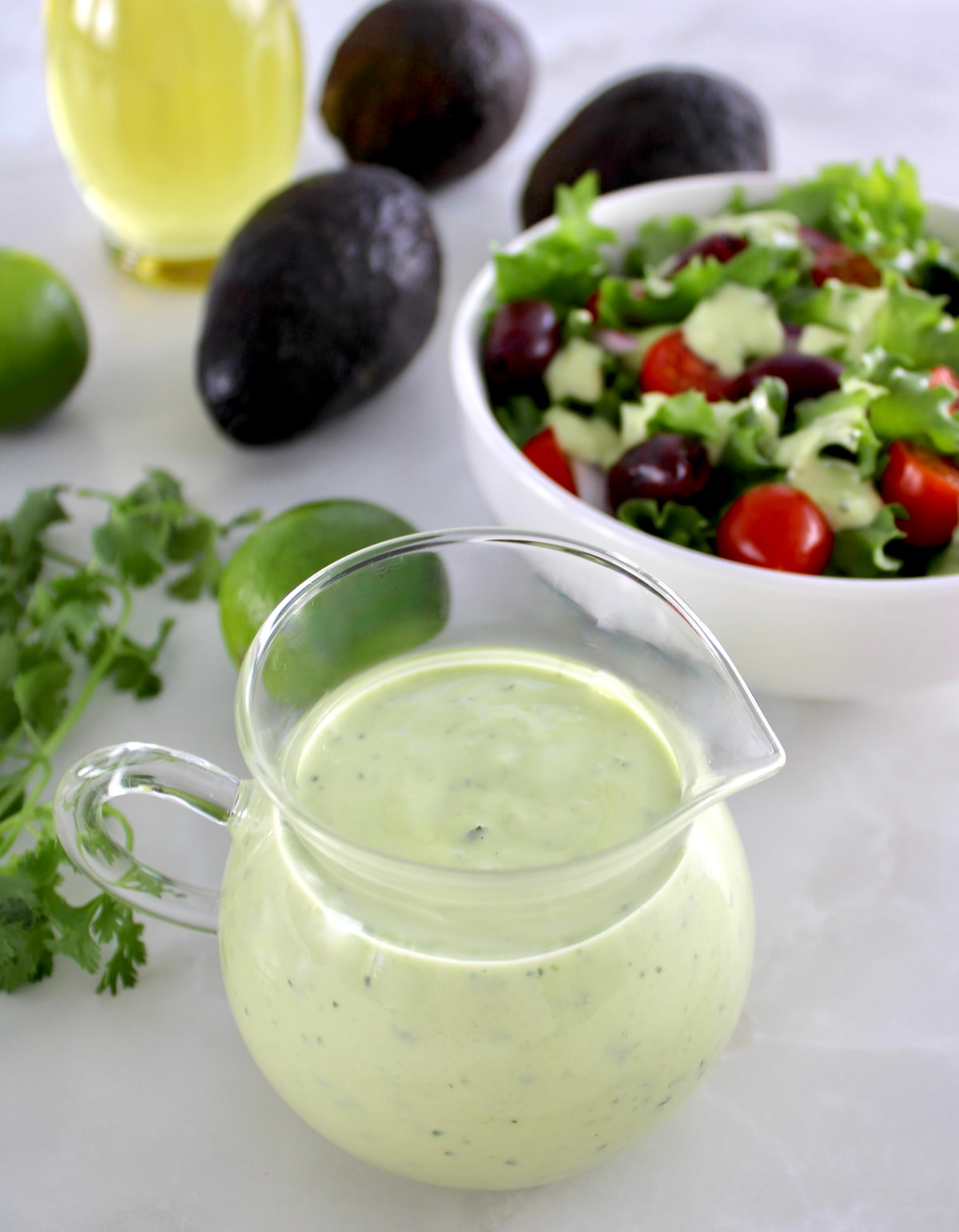 Keto Avocado Ranch Dressing in glass with salad and avocados in back
