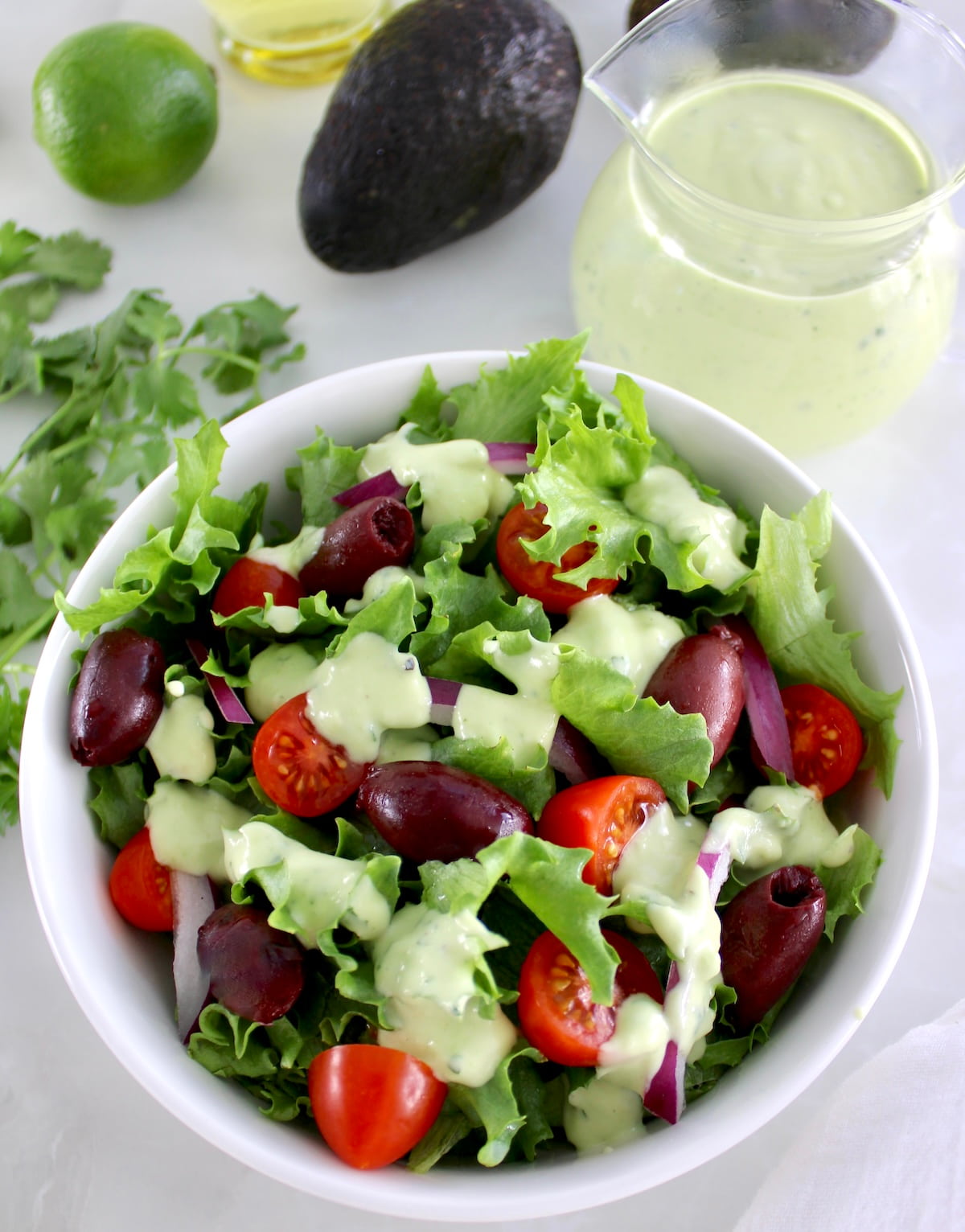 Keto Avocado Ranch Dressing over salad in white bowl with more dressing in back