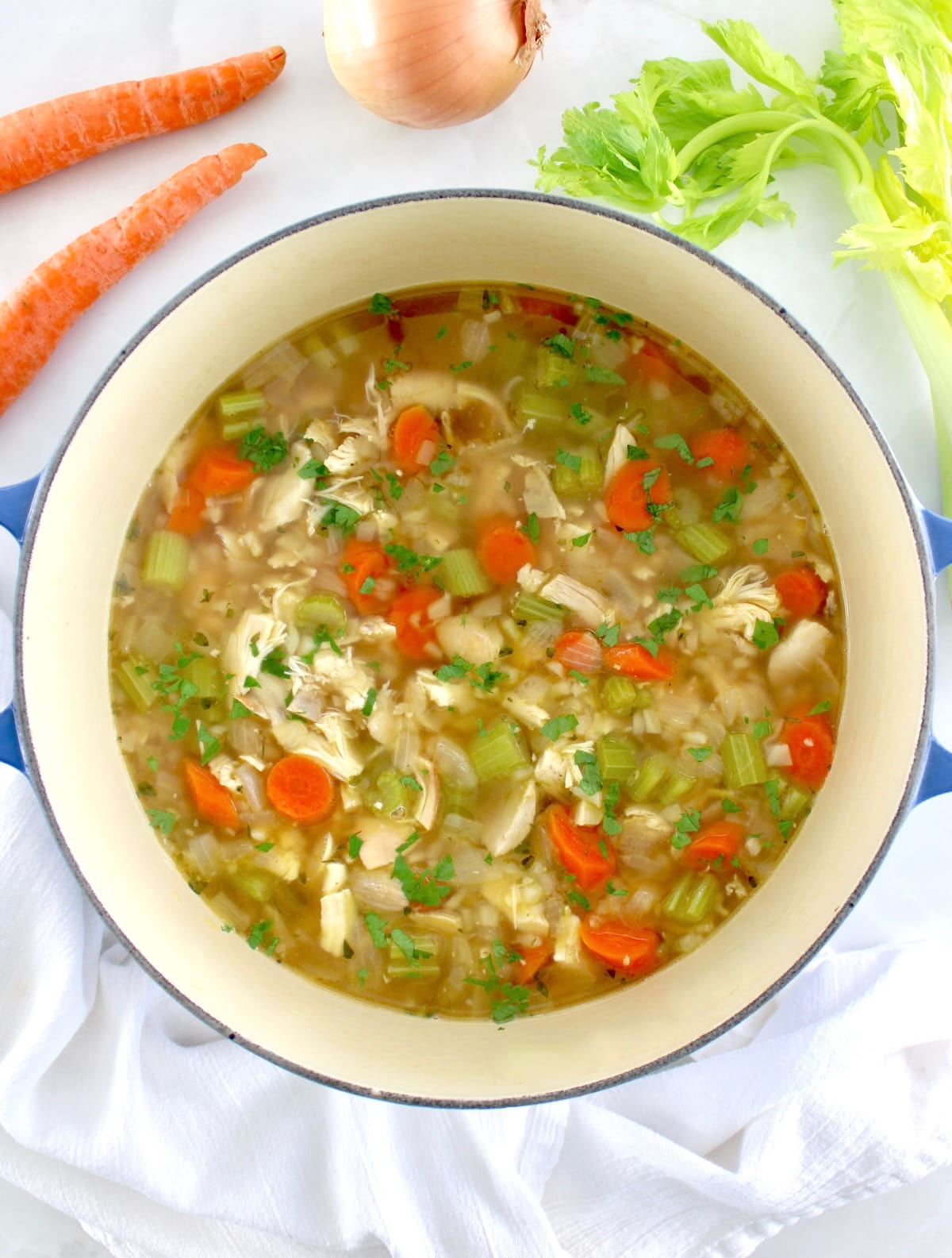 overhead view of Keto Chicken Soup with Cauliflower Rice in pot with carrots and celery in back