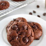 3 Keto Chocolate Almond Butter Cookies on white plate with more in back on cooling rack
