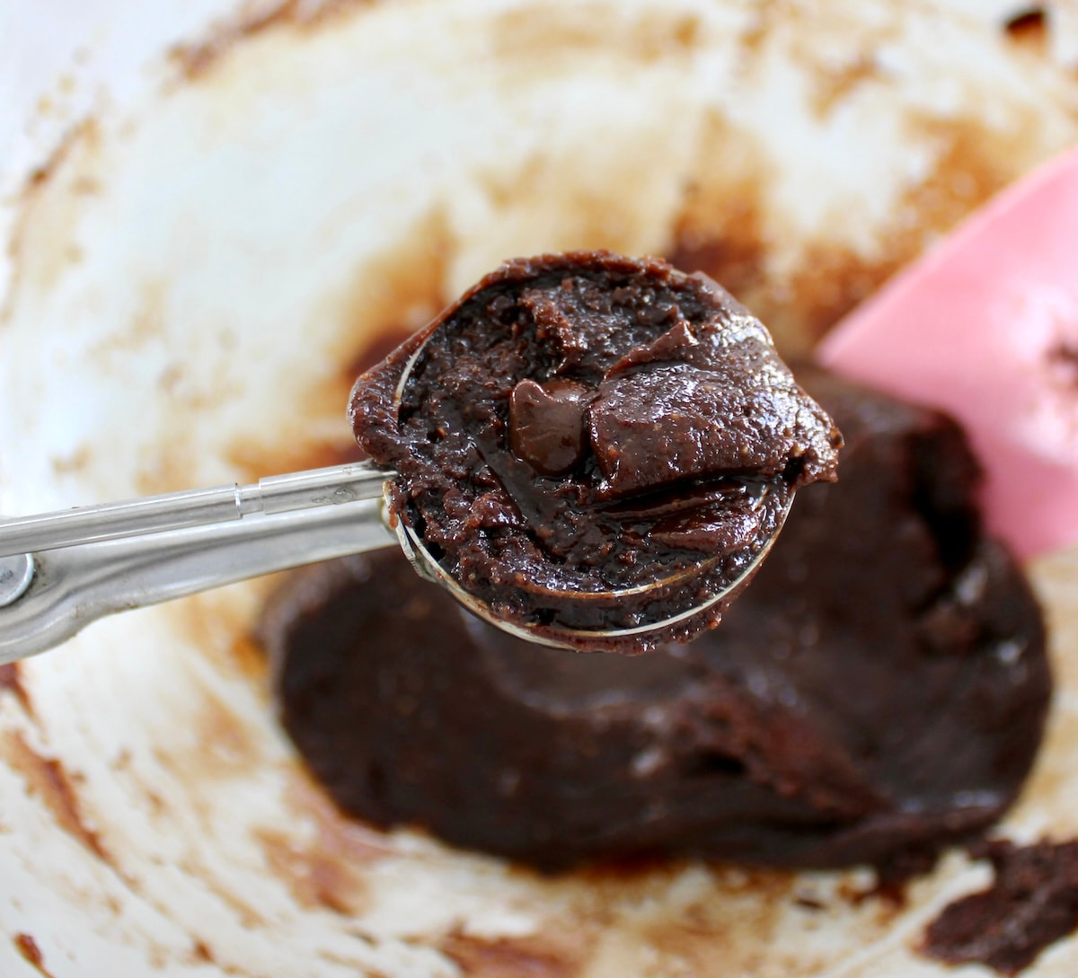 Keto Chocolate Almond Butter Cookies batter in cookie scoop held up over glass bowl