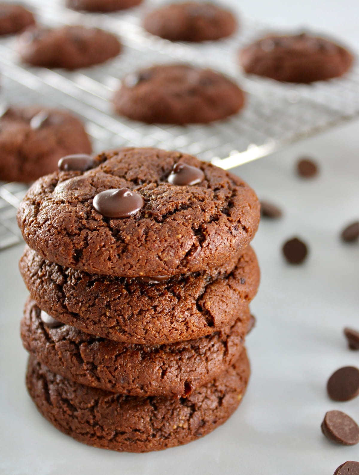 closeup of 4 Keto Chocolate Almond Butter Cookies stacked up with more on cooling rack in back